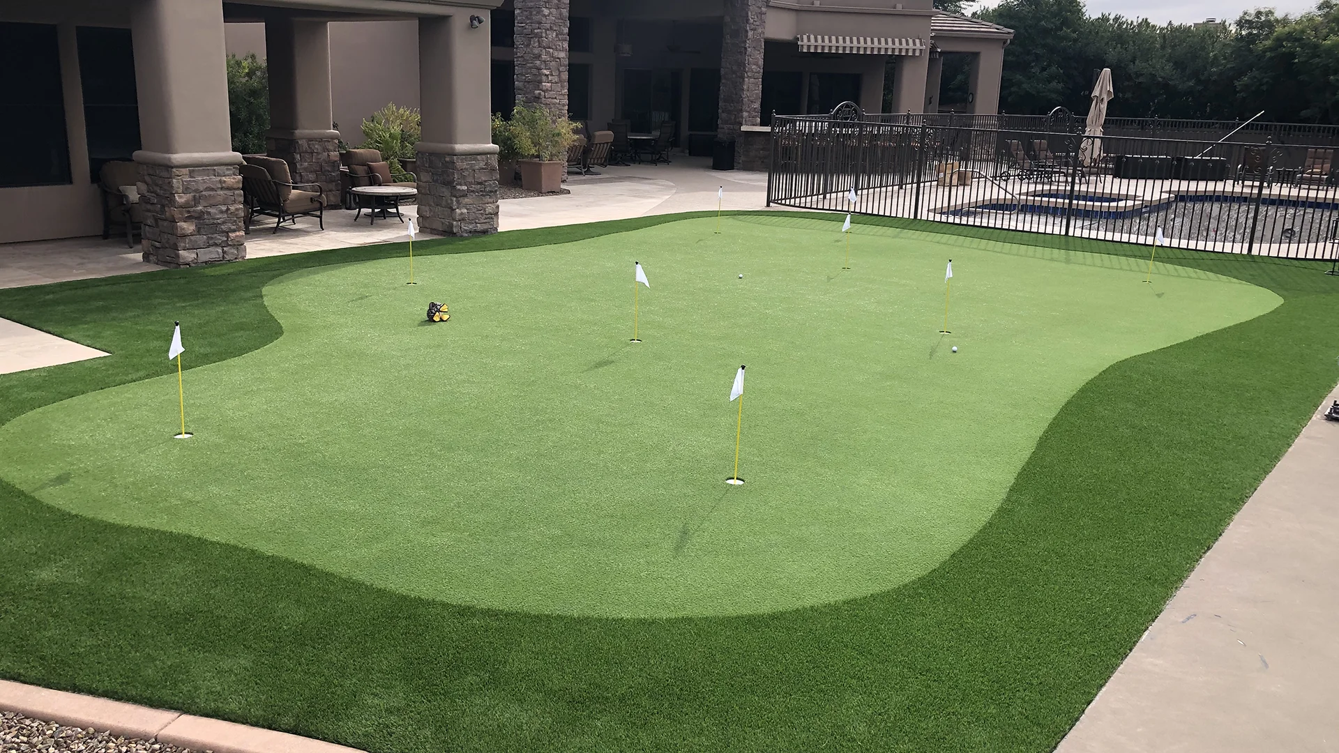 putting green next to a fenced in hot tub