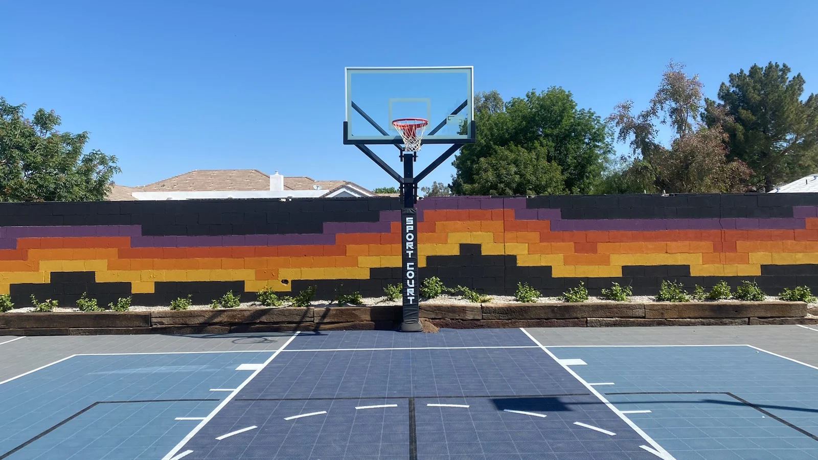 Backyard basketball court with a painted wall behind
