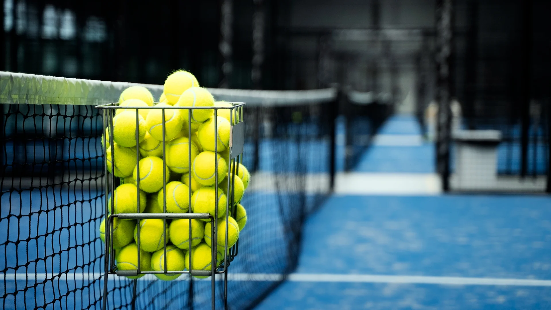close up of a basket of tennis balls on a Padel court